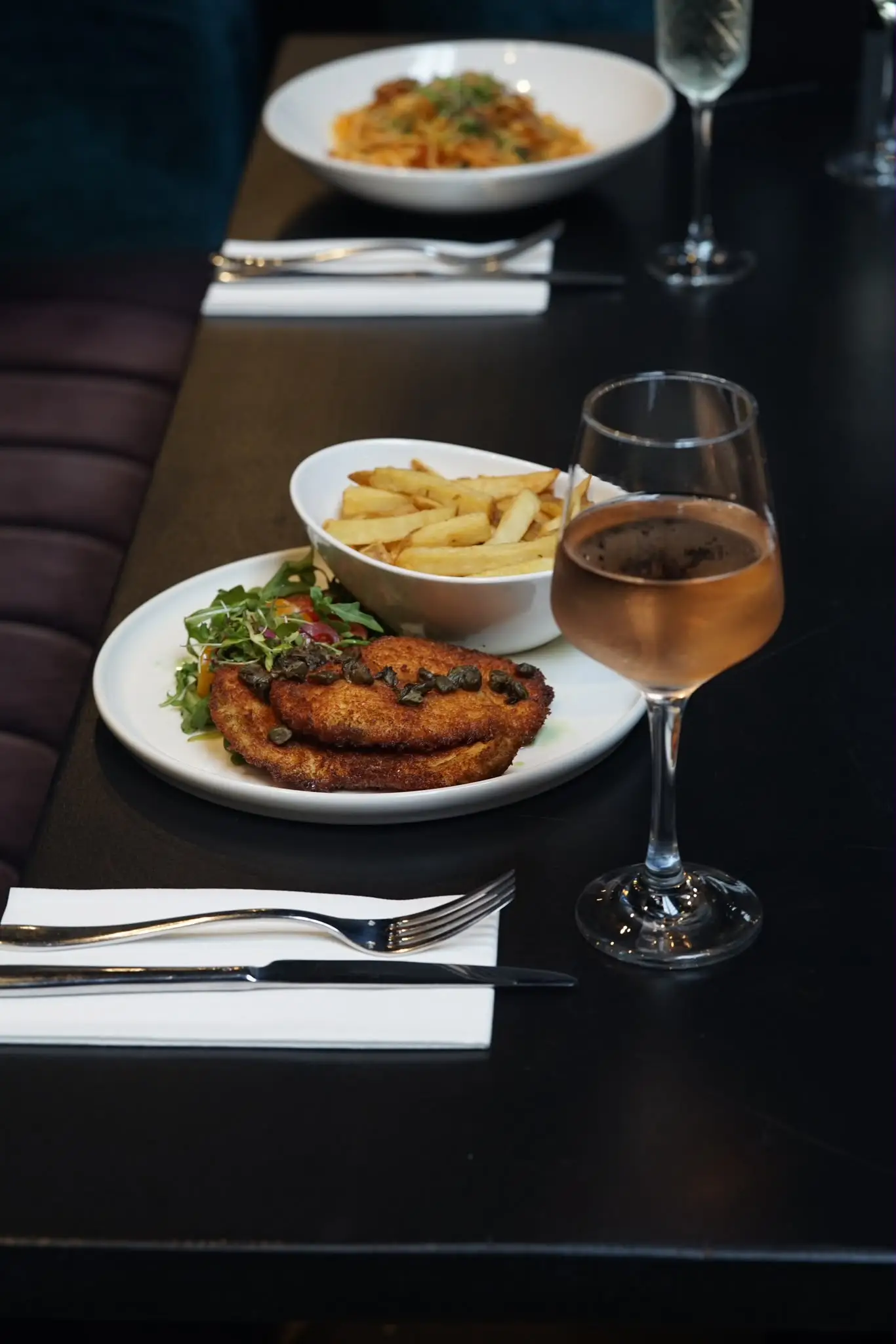 A table set with sharing plates and a glass of wine